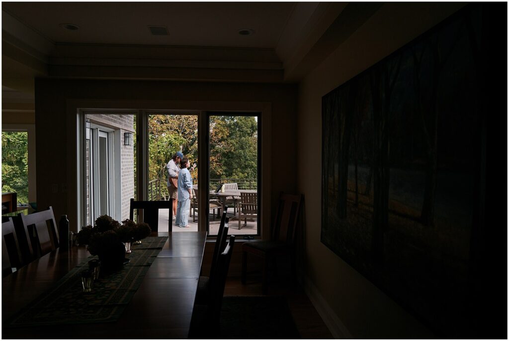 An Iowa City wedding photographer takes a photo of a wedding guest from inside a dining room.