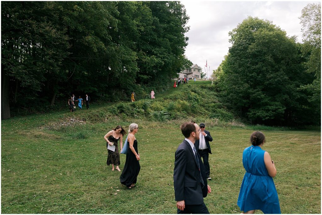 Wedding guests walk down a hill towards an outdoor wedding ceremony at a private estate.