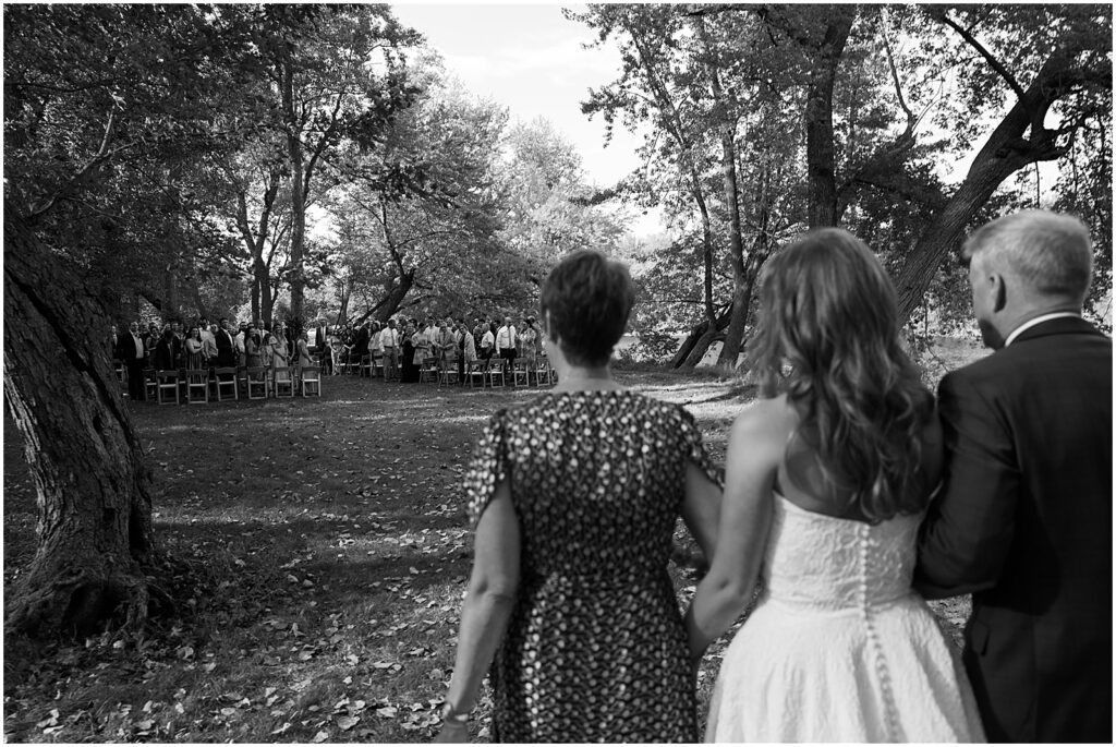 A bride's parents walk her towards a wedding ceremony at their private estate.