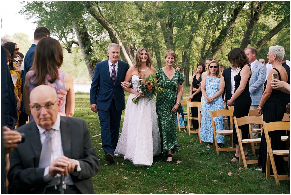 A bride walks up the aisle at an Iowa City wedding with her parents.