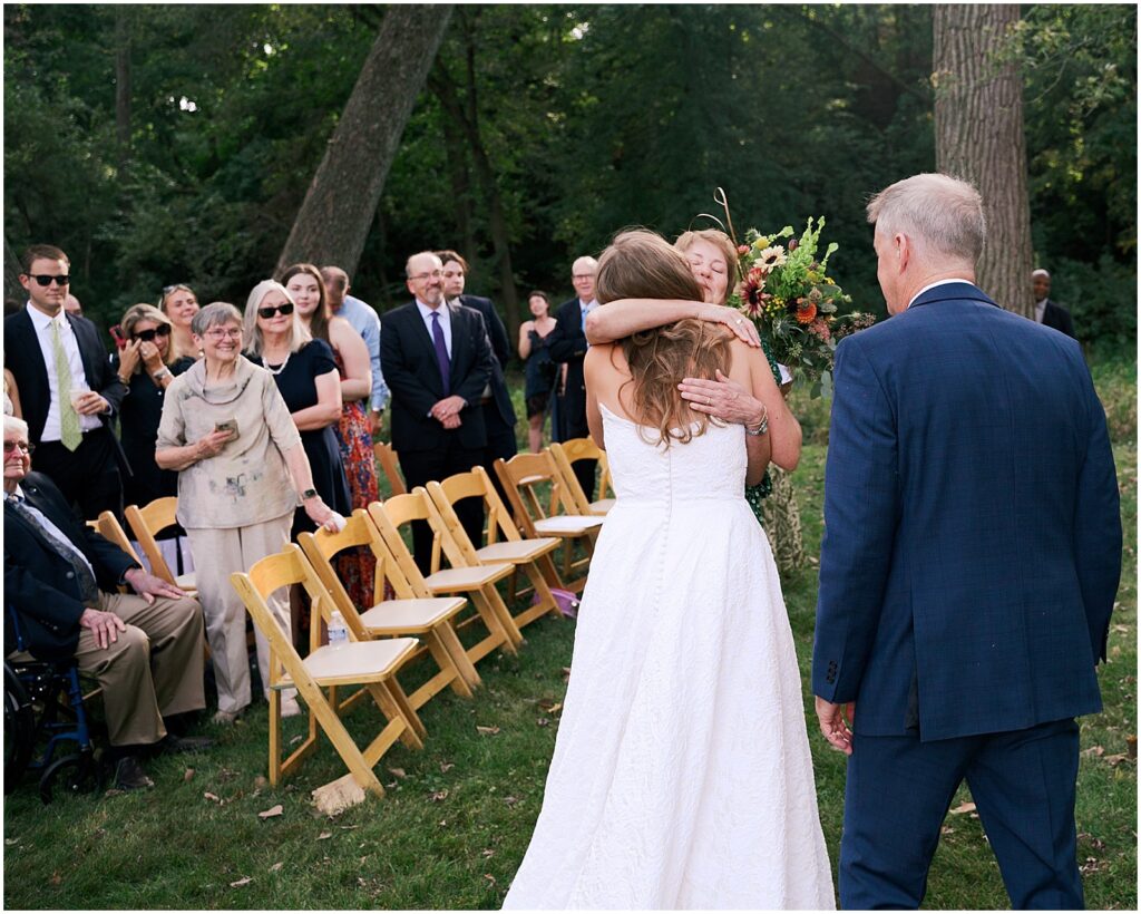 A bride hugs her mother at the start of a wedding ceremony.