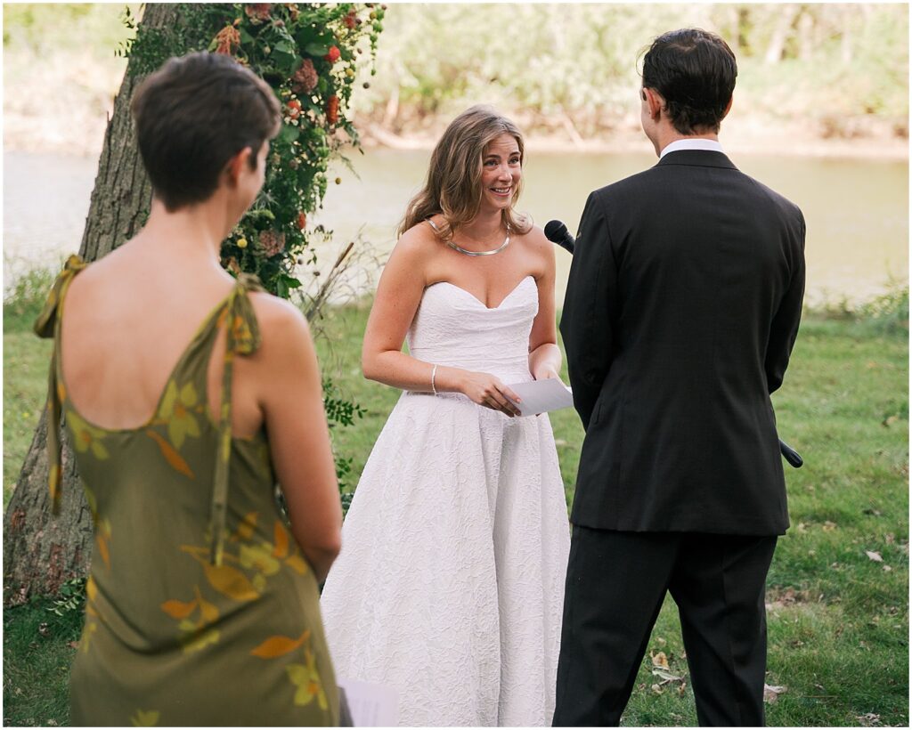 A bride reads her vows into a microphone at wedding at a private estate.