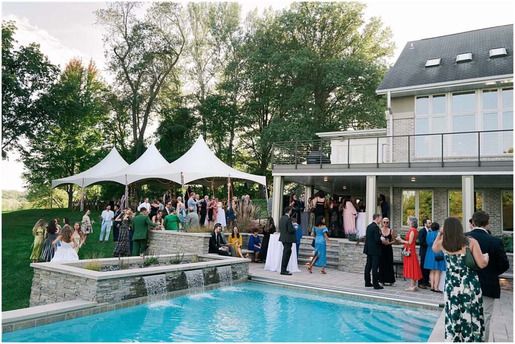 Wedding guests drink cocktails around a pool at a wedding at a private estate in Iowa City.