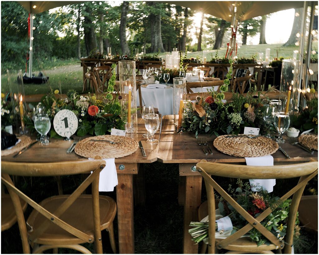 Florals and candles decorate wedding reception tables under a tent.