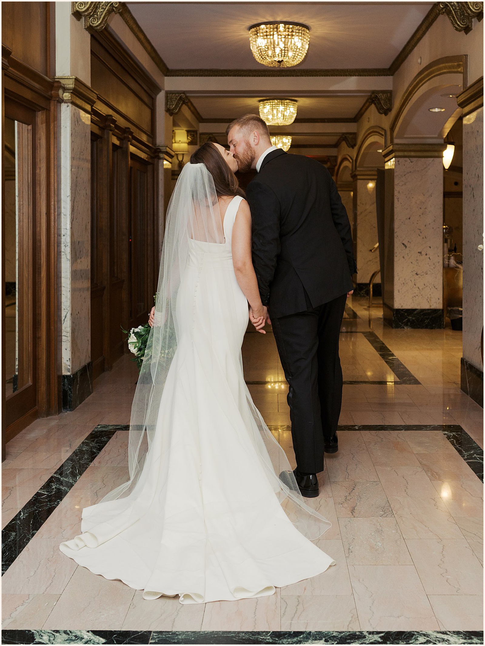 A bride and groom kiss in the hallway at their Hotel Blackhawk wedding.