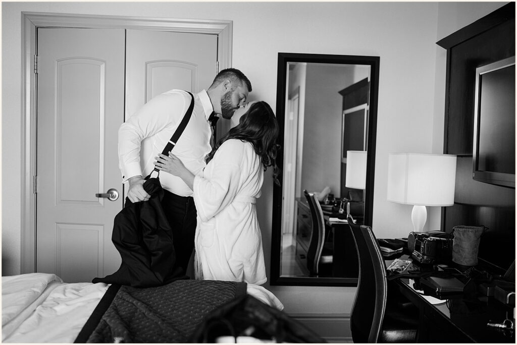 A bride and groom kiss in a hotel room at Hotel Blackhawk.