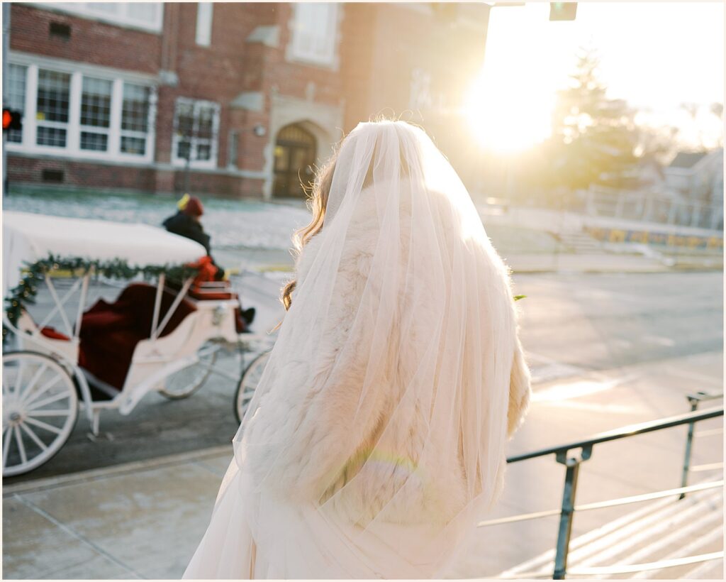 A bride walks down church steps toward a carriage.