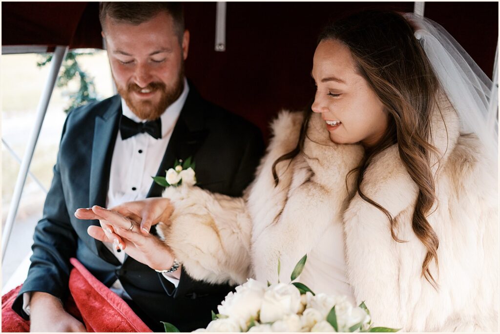 A bride and groom admire each other's rings in a candid wedding photo.