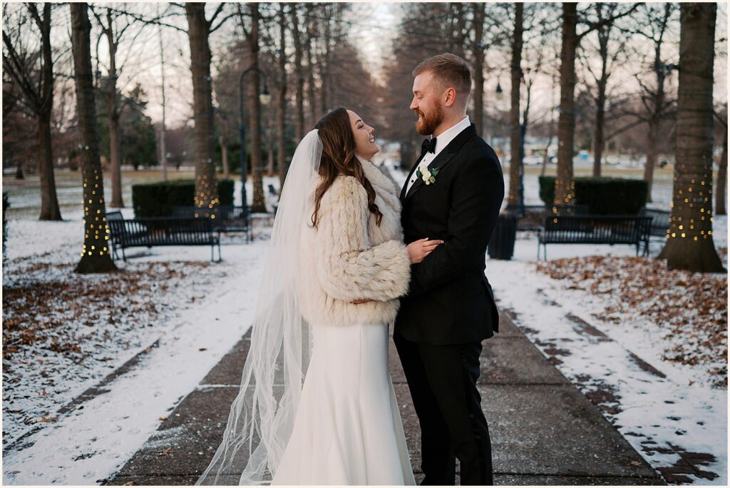 A bride and groom pose for an Iowa wedding photographer in a snowy park.