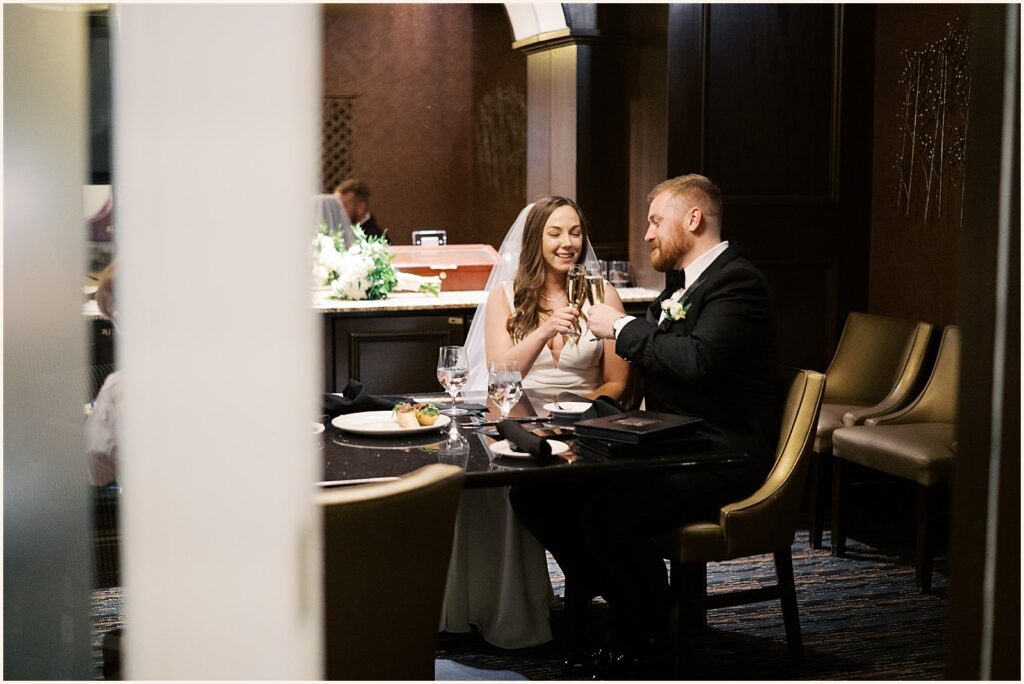 A bride and groom clink glasses in the private dining room at Hotel Blackhawk.