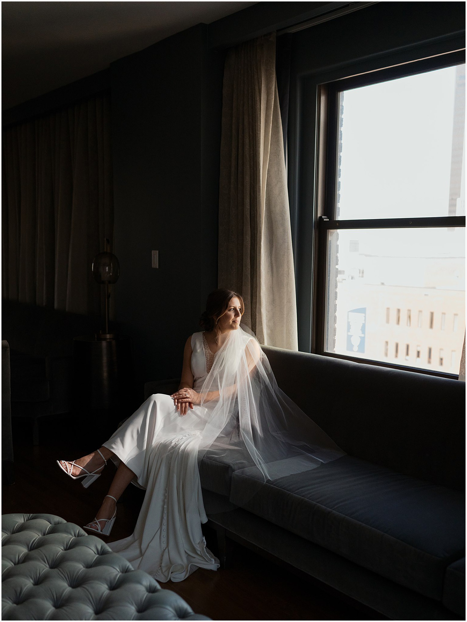 A bride sits and looks out a window inside Hotel Fort Des Moines.