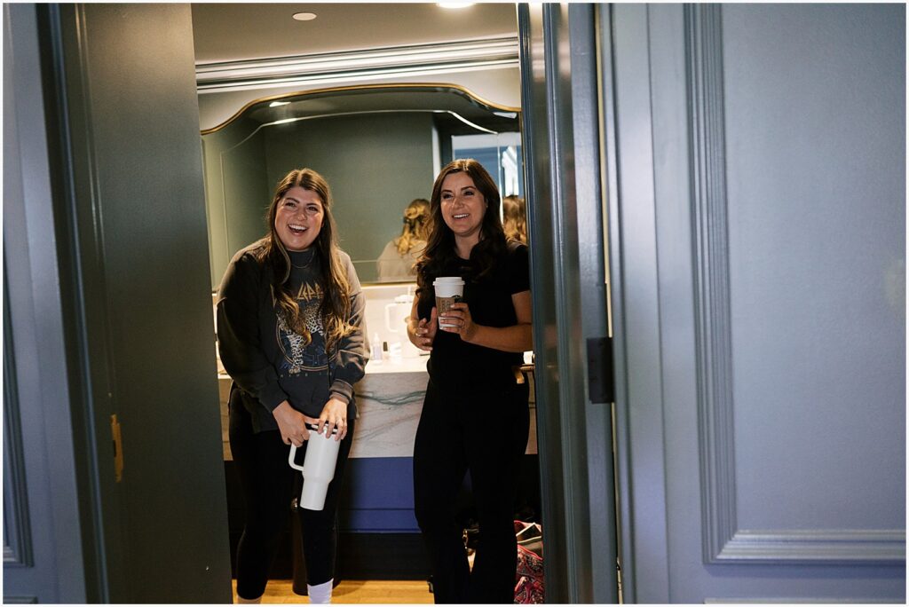 Two women stand in a hotel doorway smiling.