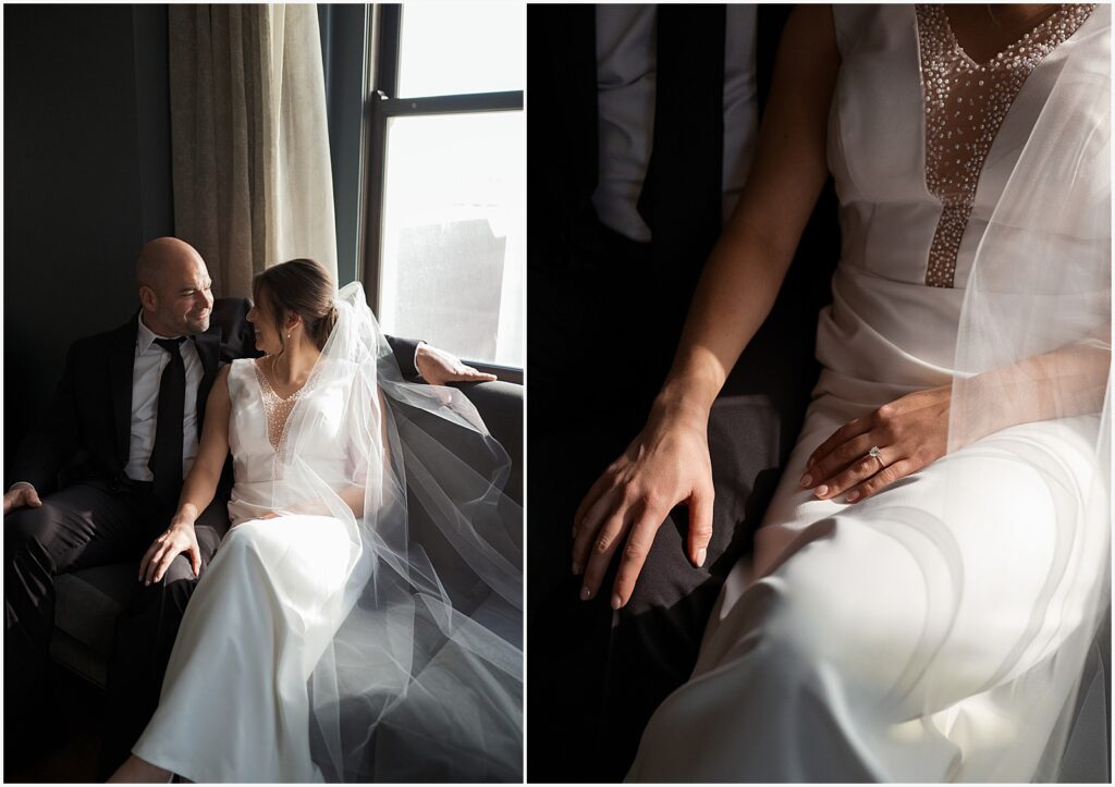 A bride and groom sit on a window seat holding hands in Hotel Fort Des Moines.