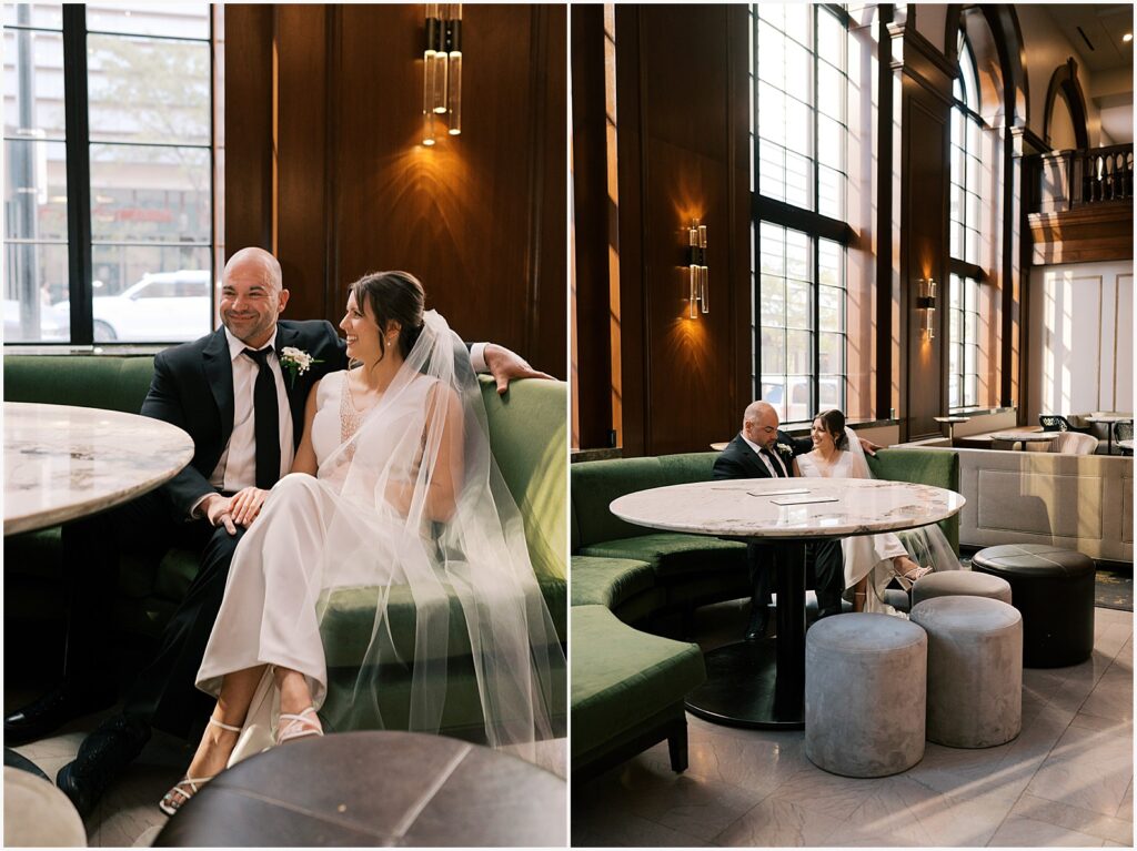 A bride and groom sit on a green couch in the lobby of Hotel Fort Des Moines