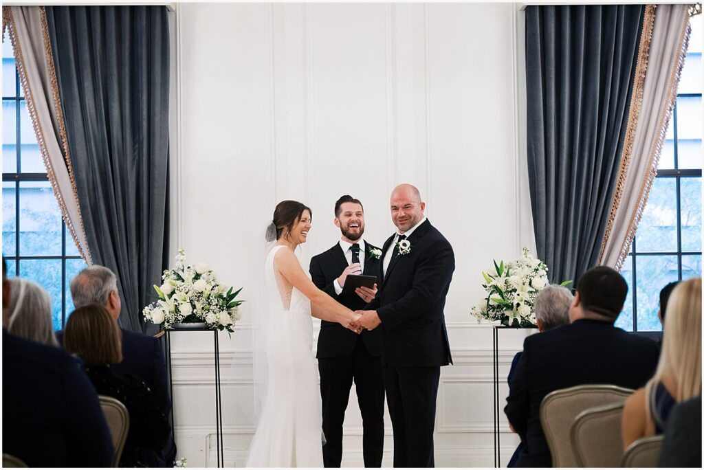 A bride and groom laugh during a wedding ceremony inside Hotel Fort Des Moines