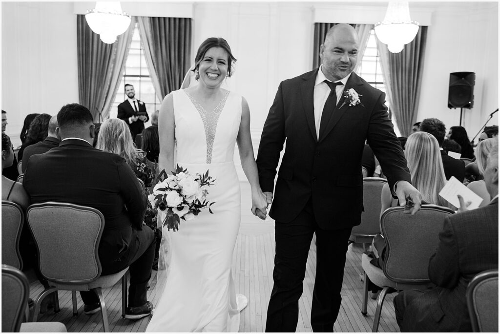 A bride and groom smile while they walk their wedding recessional.