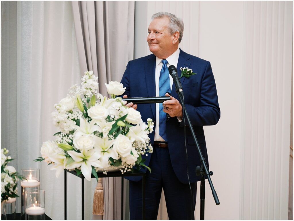 The father of a bride gives a speech into a microphone.