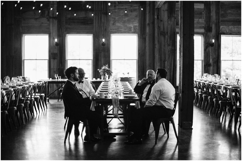 A groom and his friends sit at a reception table inside an Iowa City wedding venue.