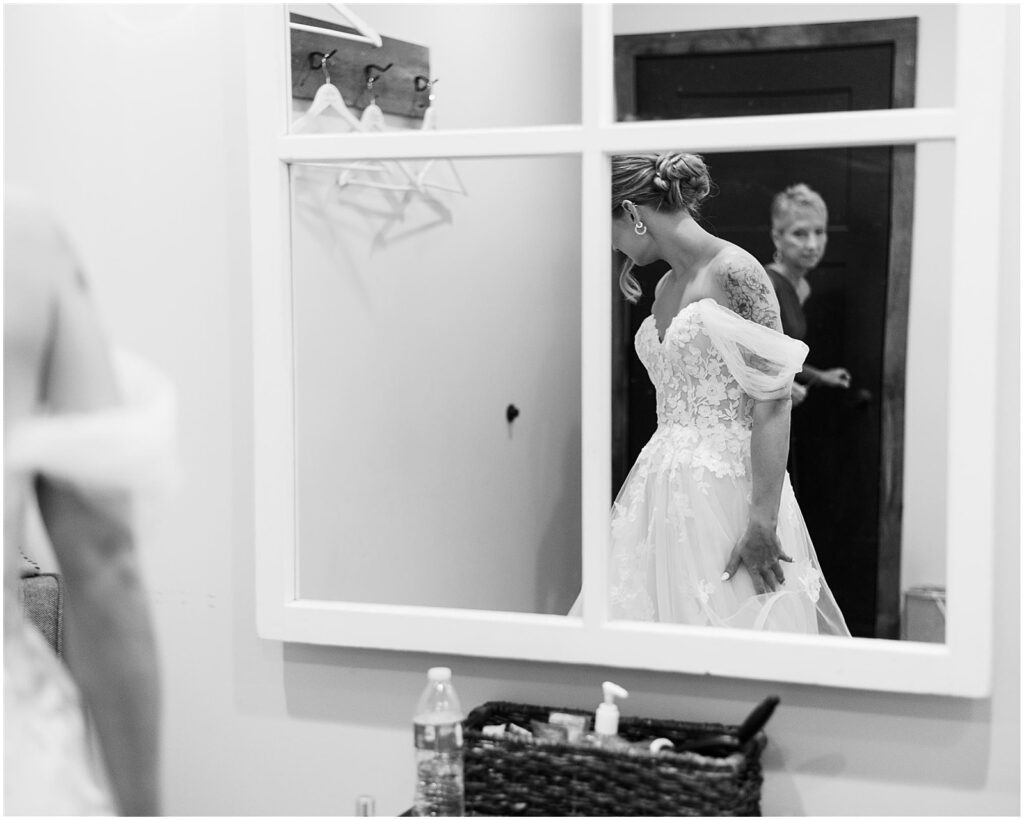 A bride walks past a mirror in an upstairs room at an Iowa wedding venue.
