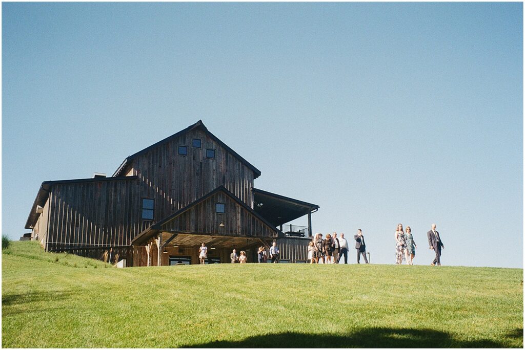 Wedding guests walk over a hill towards a wedding ceremony at Wilson's Ciderhouse.