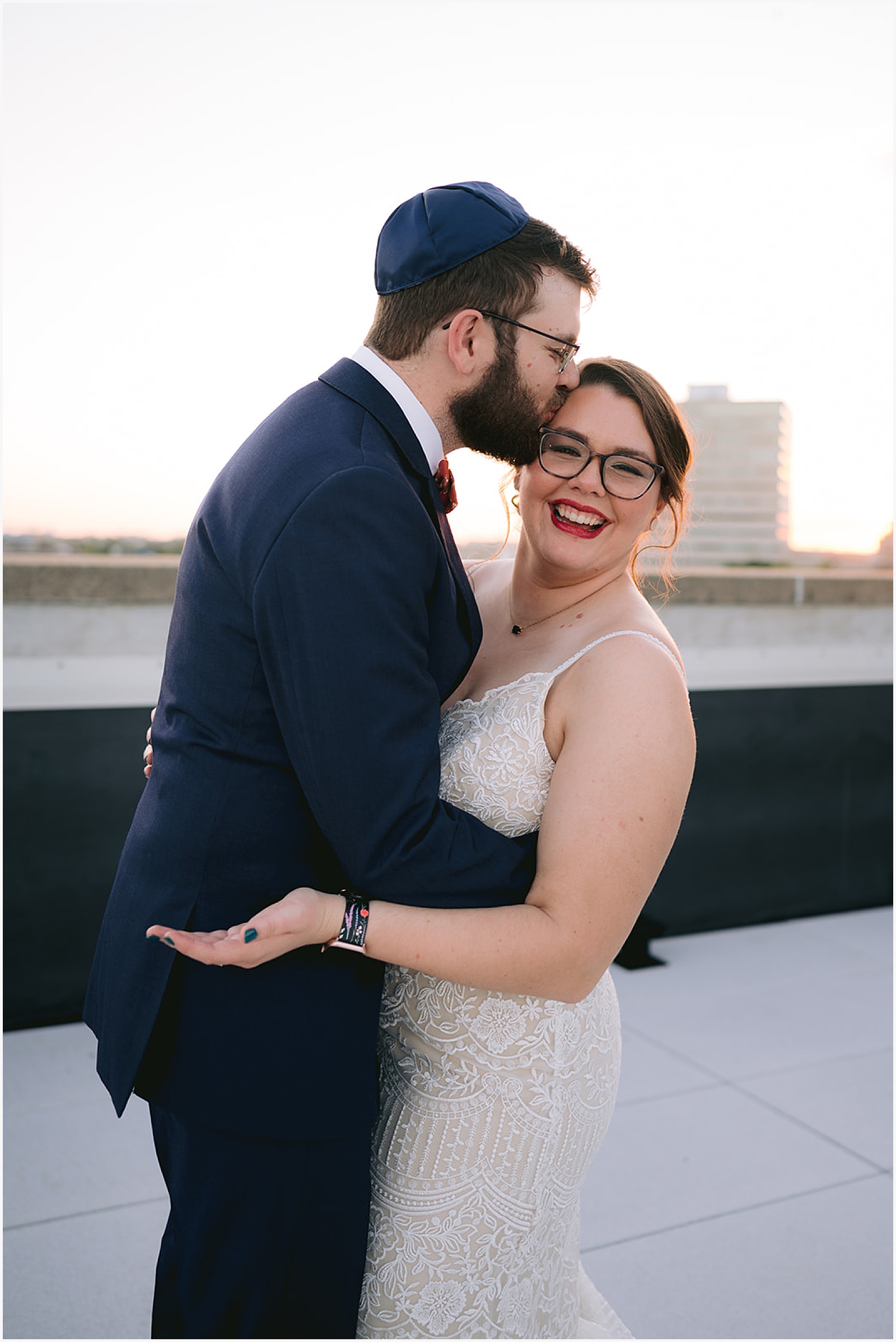 A groom kisses a bride's cheek on the rooftop of an Eastern Iowa wedding venue.