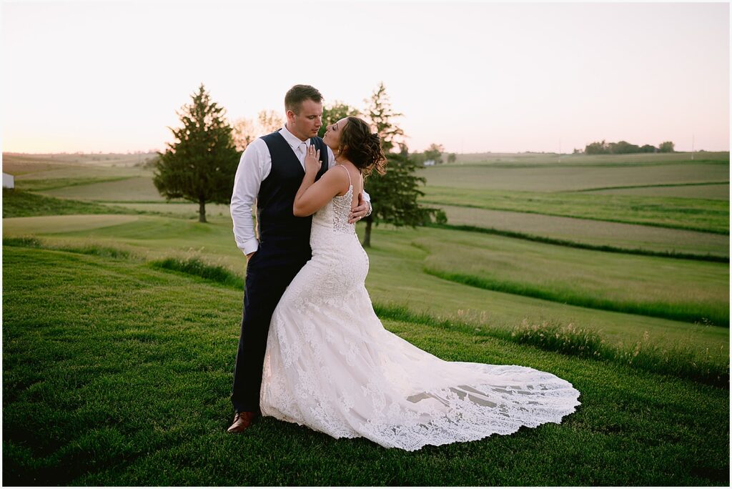 A bride and groom embrace in a field at an Eastern Iowa wedding.