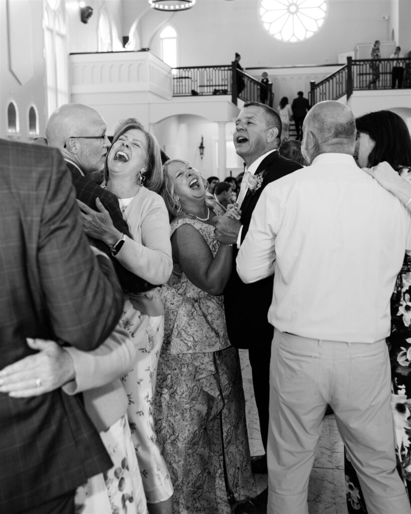Guests laughing and dancing on dance floor in celebration documented in wedding photographer documentary style